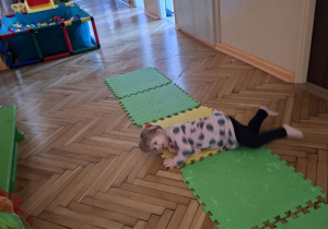 Na tym zdjeciu widać Natalkę z grupy I wykonującego ćwiczenie wspomagające rozwój fizyczny, wzmacniające mięśnie głębokie tułowia, brzucha i szyi.