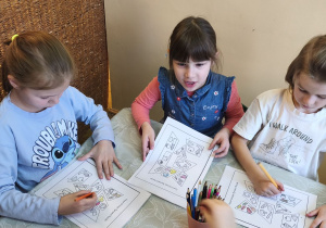 Zdjęcie przedstawia Klarę J., Kalinę oraz Julka z grupy IV wykonujacych karty pracy z elementami do piramidy zdrowego żywienia.