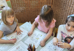 Zdjęcie przedstawia Wandę z dwiema koleżankami z grupy IV wykonujacych karty pracy z elementami do piramidy zdrowego żywienia.