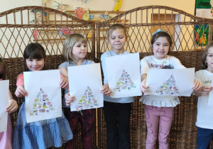 Zdjęcie przedstawia dziewczynki biorące udział w zajęciu, które prezentują wykonane przez siebie piramidy zdrowego żywienia.