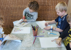 Na tym zdjęciu widać Oliwię, Mikołaja, Adasia M. oraz Adsia W., którzy wycinają elementy do piramidy zdrowego żywienia.