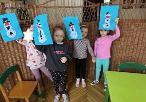Zdjęcie przedstawia czworo dzieci prezentujących gotowe prace - bałwanki.