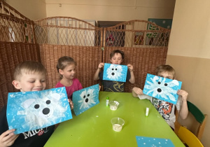 Zdjęcie przedstawia czworo dzieci prezentujących gotowe prace - misie polarne.