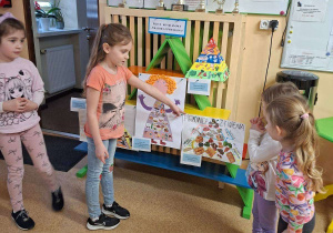 Na tym zdjęciu widać Zuzię M., która pokazuje swoją pracę oraz pozostałe uczestniczki konkursu.