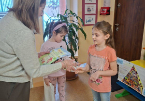 Zdjęcie przedstawia panią dyrektor wręczjącą nagrodę Zuzi M. za udział w konkursie.