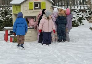 Zdjęcie przedstawia dzieci podczas zimowych zabaw w ogrodzie.