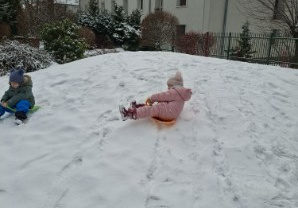 Zdjęcie przedstawia jedną z dziewczynek zjeżdżającą z górki na jabłuszku.