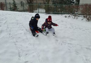 Zdjęcie przedstawia dwóch chłopców zjeżdżających z górki na jabłuszku.