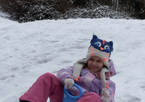 Zdjęcie przedstawia Olę zjeżdżającą na jabłuszku z górki.