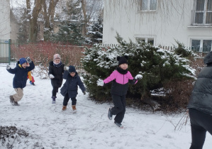 Zdjęcie przedstawia dzieci bawiące się w śnieżki.
