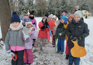 Na tym zdjęciu widać dzieci z jabłuszkami w rękach przed górką.