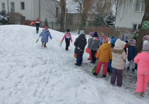 Na tym zdjęciu widać dzieci oczekujące przed górką na zjazd na jabłuszku.