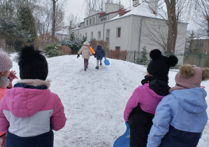 Na tym zdjęciu widać dzieci oczekujące przed górką na zjazd na jabłuszku.
