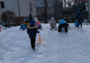 Zdjęcie przedstawia dzieci zjeżdżające z górki na jabłuszkach.