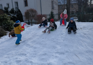 Zdjęcie przedstawia dzieci zjeżdżające z górki na jabłuszkach.