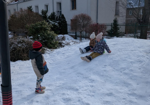 Zdjęcie przedstawia dzieci zjeżdżające z górki na jabłuszkach.