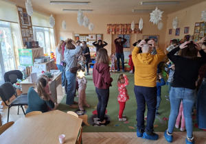 Zdjęcie przedstawia rodziców i dzieci podczas wspólnych zabaw przy muzyce.