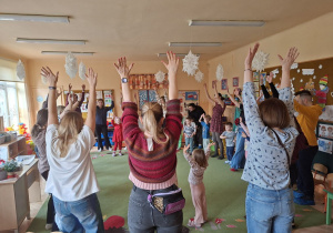 Zdjęcie przedstawia rodziców i dzieci podczas wspólnych zabaw przy muzyce.