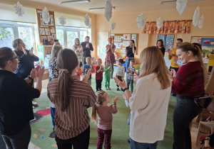 Zdjęcie przedstawia rodziców i dzieci podczas wspólnych zabaw przy muzyce.