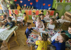 Na tym zdjęciu widać dzieci siedzące przy stolikach.