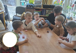 Na tym zdjęciu widać Henia P. napełniającego foremkę płynną czekoladą oraz inne dzieci.