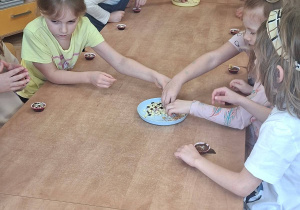 Na tym zdjęciu widać dzieci ozdabiające sowje czekoladki.