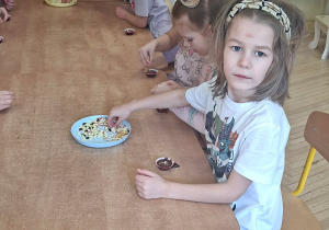 Zdjęcie przedstawia Julka Ch. oraz inne dzieci ozdabiające swoje pralinki.
