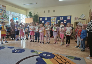 Zdjęcie przedstawia kilkoro dzieci z grupy IV recytujących wiersz o witaminach zawartych w owocach i warzywach.