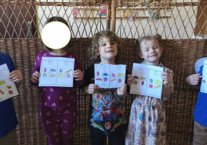 Zdjęcie przedstawia dwie dziewczynki oraz trzech chłopców z grupy III prezentujących wykonane przez siebie karty pracy.