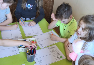 Na tym zdjęciu widać trzy dziewczynki oraz dwóch chłopców z grupy IV podczas wykonywania karty pracy.