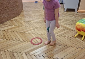 Na tym zdjęciu widać Jagodę L. z grupy II wykonującą ćwiczenie przeciw koślawości kolan z przyborem.