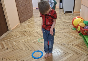 Na tym zdjęciu widać Filpa L. z grupy IV wykonującego ćwiczenie przeciw koślawości kolan z przyborem.