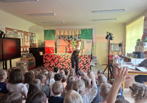 Zdjęcie przedstawia jedną z aktorek teatru ''Pacuś" witającą dzieci na przedstawieniu.