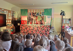 Na tym zdjęciu widać jedną ze scen teatrzyku i dzieci oglądające przedstawienie.