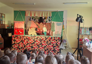 Na tym zdjęciu widać jedną ze scen teatrzyku i dzieci oglądające przedstawienie.