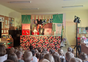 Na tym zdjęciu widać jedną ze scen teatrzyku i dzieci oglądające przedstawienie.