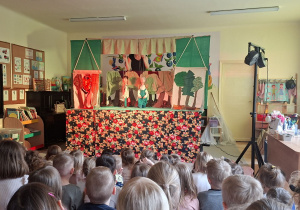 Na tym zdjęciu widać jedną ze scen teatrzyku i dzieci oglądające przedstawienie.