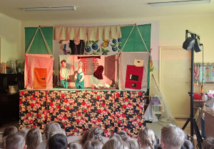 Na tym zdjęciu widać jedną ze scen teatrzyku i dzieci oglądające przedstawienie.