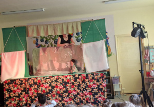 Na tym zdjęciu widać jedną ze scen teatrzyku i dzieci oglądające przedstawienie.