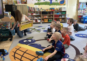 Na tym zdjęciu widać prowadzącą warsztaty, która prezentuje dzieciom z grupy III japońskie liczydło - soroban.