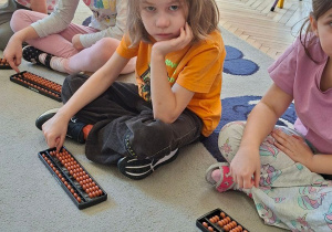 Zdjęcie przedstawia Julka z grupy IV z koleżankami przy sorobanach.