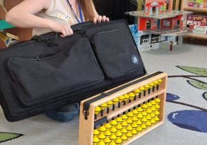 Na tym zdjęciu widać prowadzącą warsztaty, która prezentuje dzieciom japońskie liczydło - soroban.