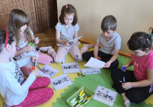 Zdjęcie przedstawia pięcioro dzieci z grupy IV wykonujące kartę pracy "Dopasuj minki do sytuacji".
