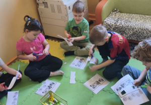 Zdjęcie przedstawia pięcioro dzieci z grupy IV wykonujące kartę pracy "Dopasuj minki do sytuacji".