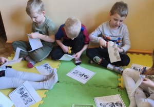 Zdjęcie przedstawia pięcioro dzieci z grupy III wykonujące kartę pracy "Dopasuj minki do sytuacji".