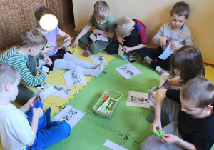 Zdjęcie przedstawia pięcioro dzieci z grupy III wykonujące kartę pracy "Dopasuj minki do sytuacji".