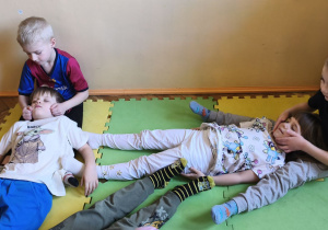 Zdjęcie przedstawia czworo dzieci z grupy III podczas wykonywania masażyku relaksującego.