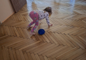 Zdjęcie przedstawia Lenę R. z grupy I podczas czworakowania slalomem między jeżykami.