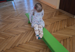 Na tym zdjęciu widać Natalkę z grupy I wykonującą przenoszenie woreczka stopami na drugą stronę ławeczki.