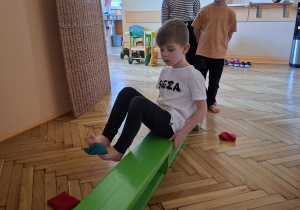 Na tym zdjęciu widać Filipa L. z grupy IV wykonującego przenoszenie woreczka stopami na drugą stronę ławeczki.